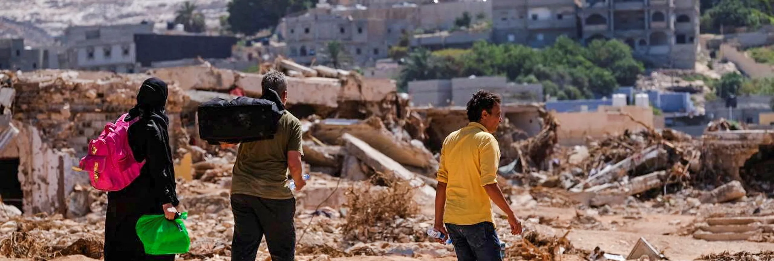 Libya. People Carrying Belongings Amidst Flood Debris