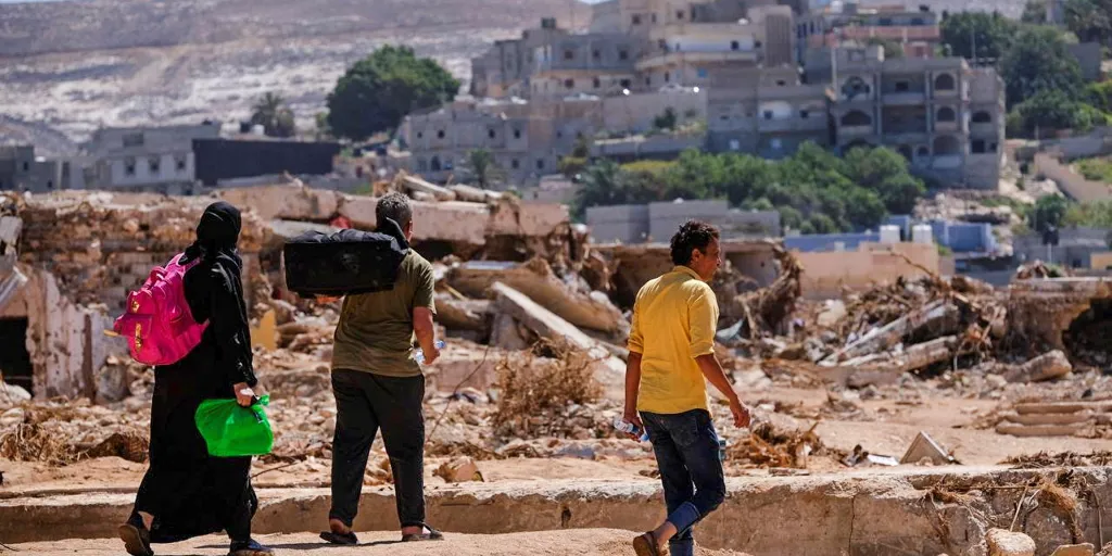 Libya. People Carrying Belongings Amidst Flood Debris