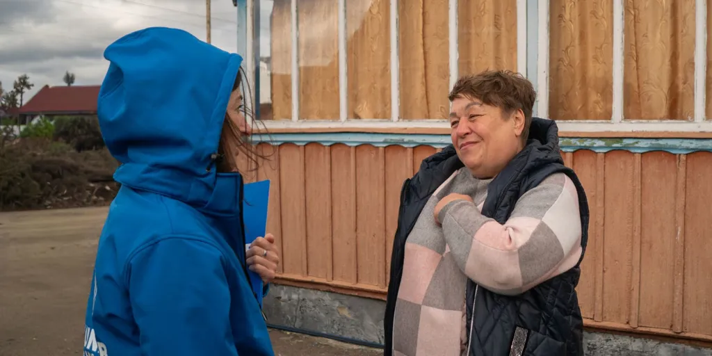 A UNHCR staff member speaks with Larysa outside her home in central Ukraine, where UNHCR supported repairs to improve living conditions for displaced families.