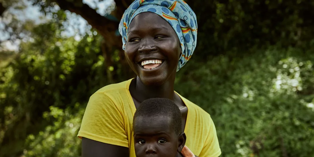 Woman laughing, holding baby. South Sudanese refugee, Bety Aredu, 22, holds her seven-month-old baby, Sarah, at Biringi settlement, Ituri province, north-east Democratic Republic of Congo, where she receives support from UNHCR.