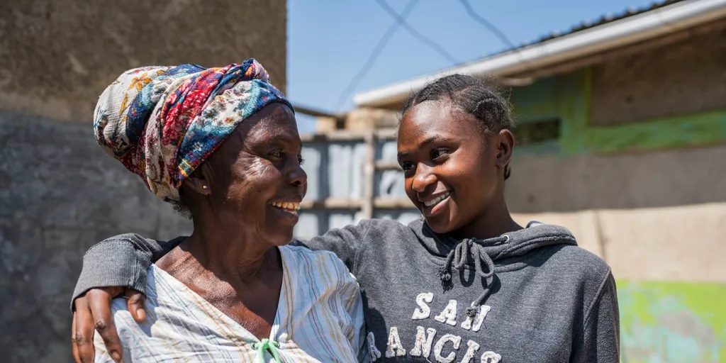 Omwali* and her grandmother Nia* outside their home in Nakivale refugee settlement.